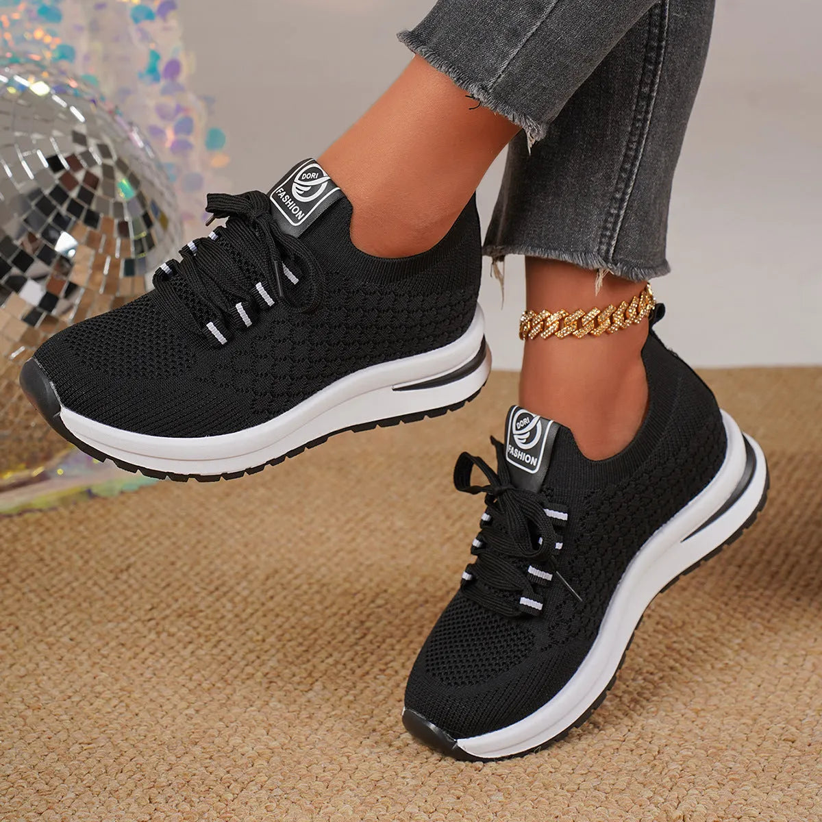 Black and white women's flat lace-up mesh sneakers with round toe on a rubber sole.