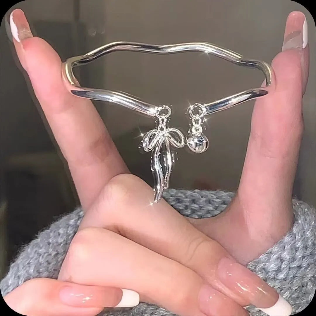 Silver adjustable bracelet with a detailed bow charm clasp on a white background.