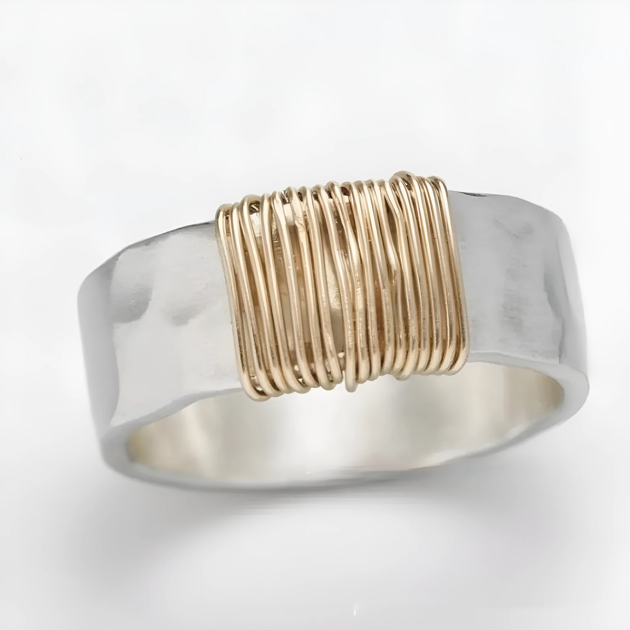 Geometric copper ring bracelet with a wide face and irregular coil design in a silver gold colour.