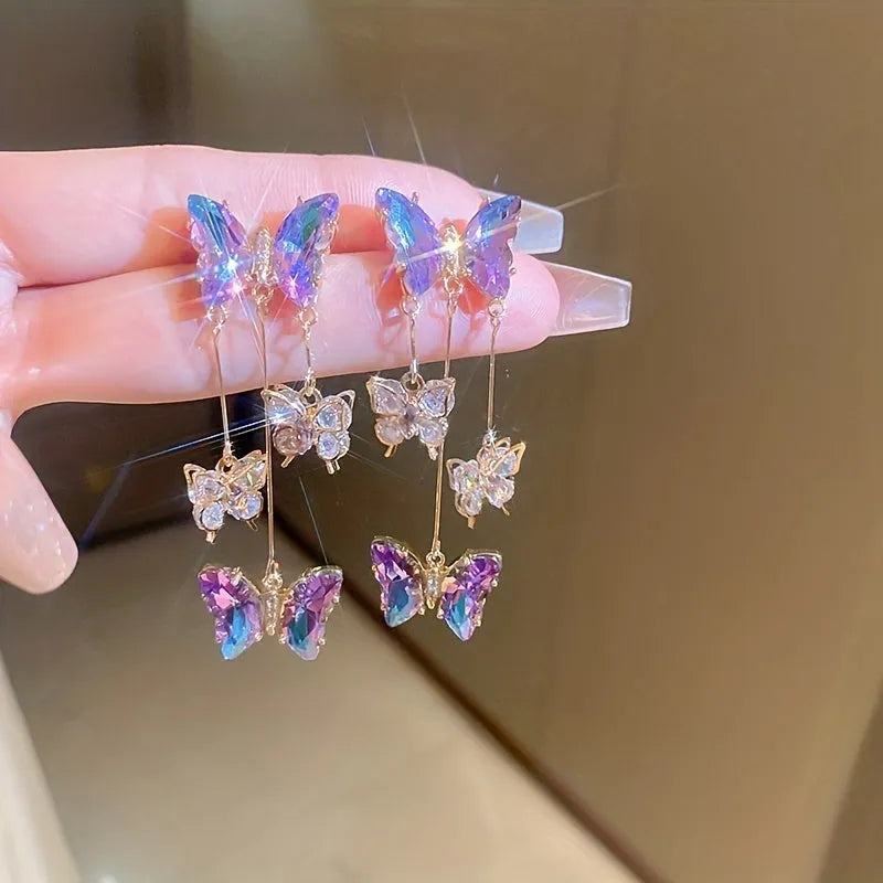 A pair of blue purple butterfly tassel drop earrings with crystal flowers and silver needle details on alloy.