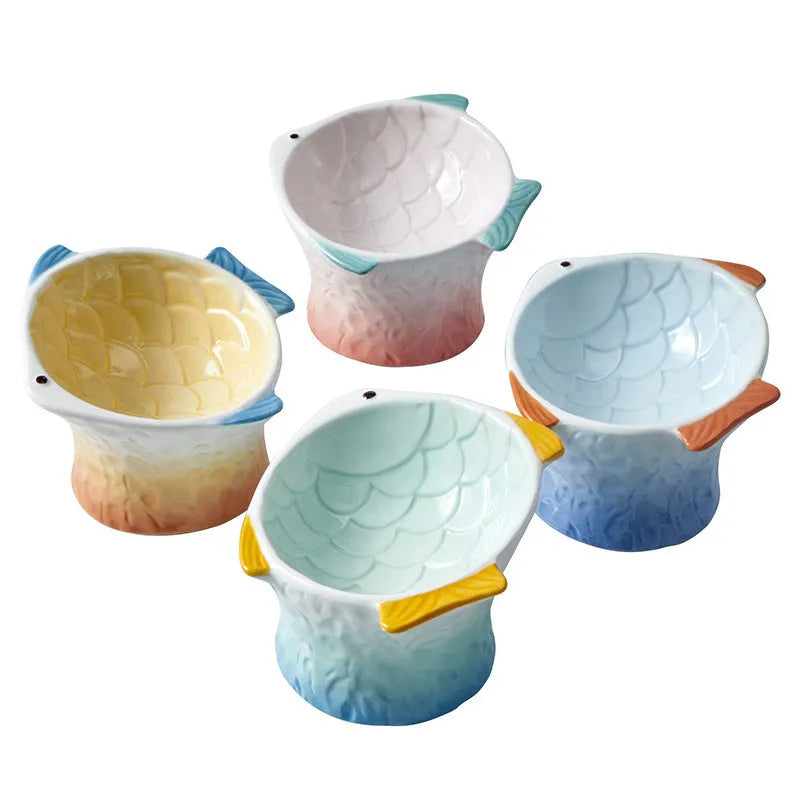 Set of four blue, fish-shaped ceramic cat bowls with a tilted design on a kitchen counter.