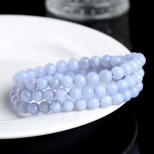 A blue agate bracelet with a natural striped pattern and scattered beads on a wrist.