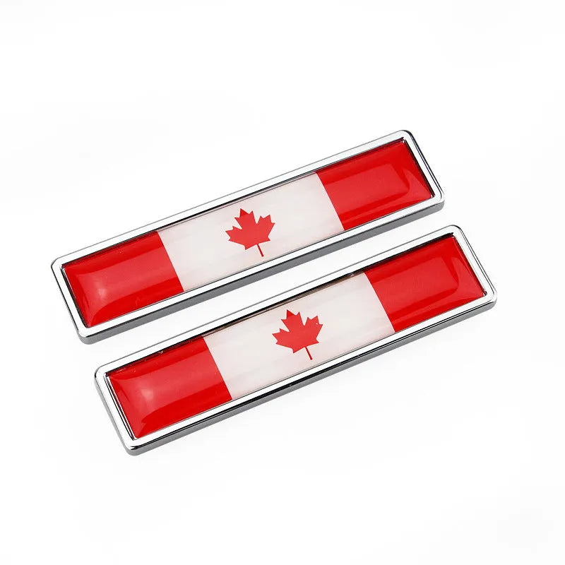 A pair of silver zinc alloy car badge labels with coloured national flag designs, shown at 58mm by 14mm scale.