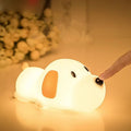 Small two-tone cartoon dog shaped silicone night lamp with USB charging port.