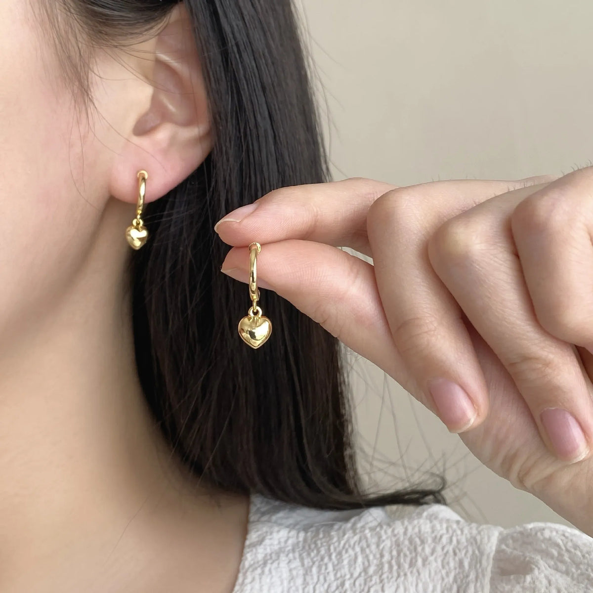 Pair of copper heart-shaped C-style earrings in gold electroplated finish on white background