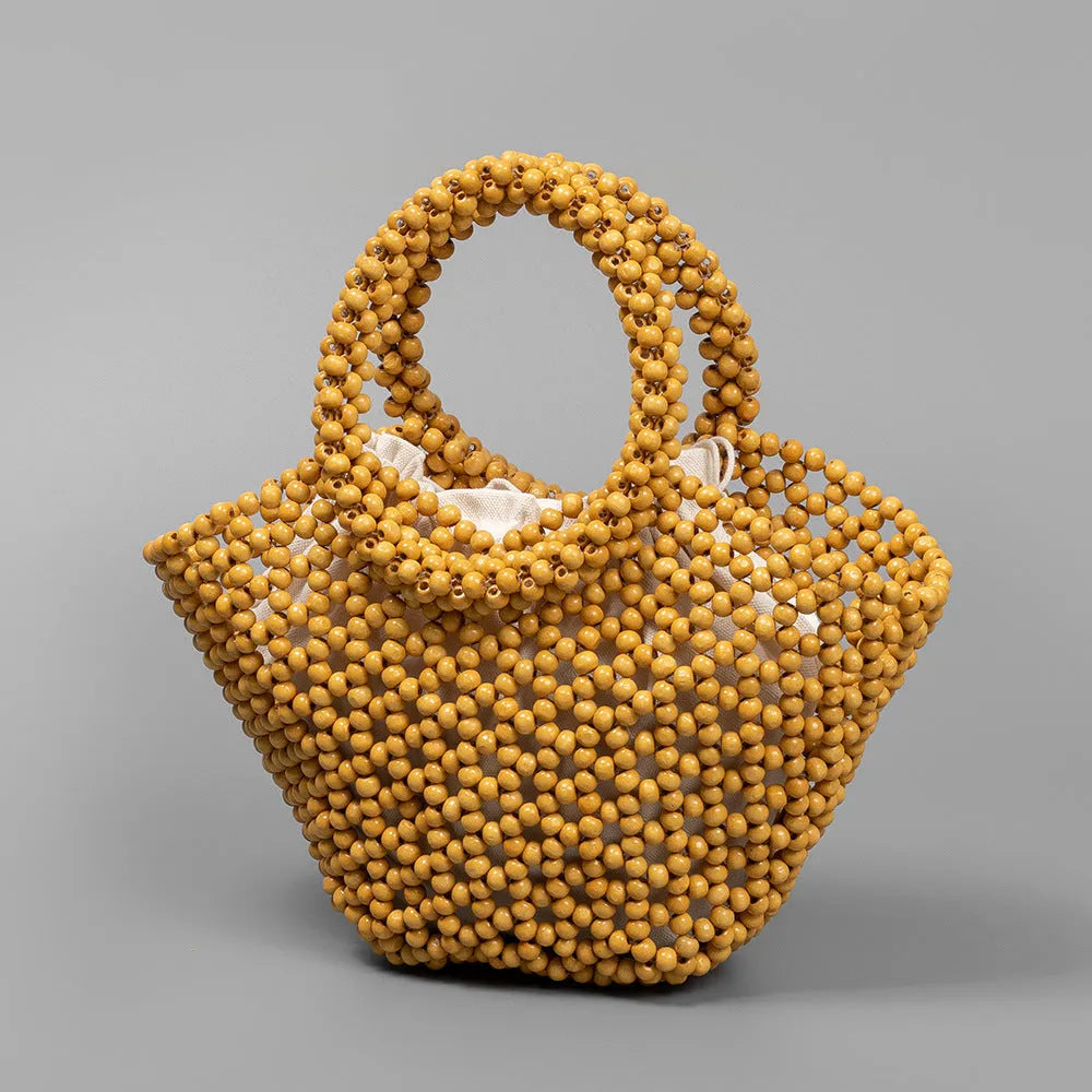 Hand-woven dumpling-shaped beach bag with wooden beads in milky white.