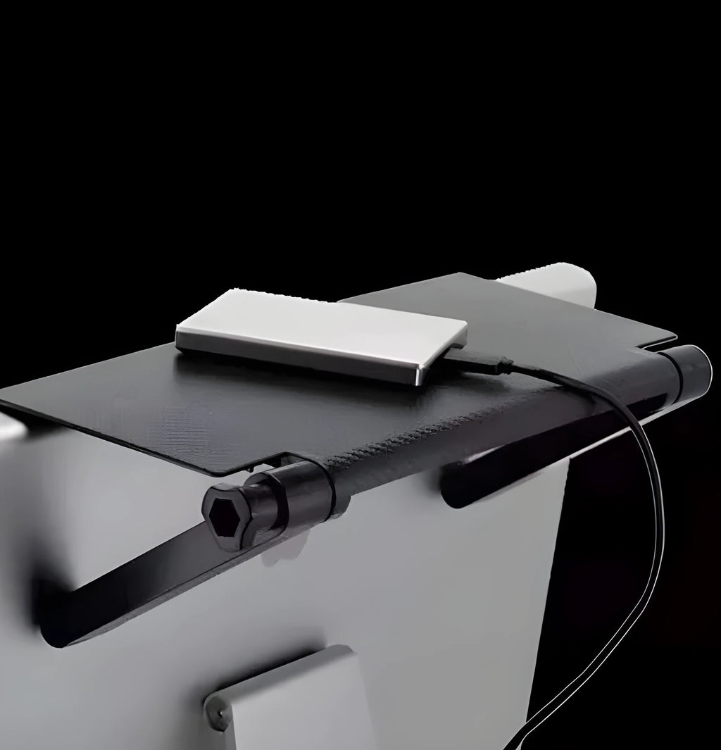 Black adjustable screen top shelf mounted on a monitor holding a streaming device and remote