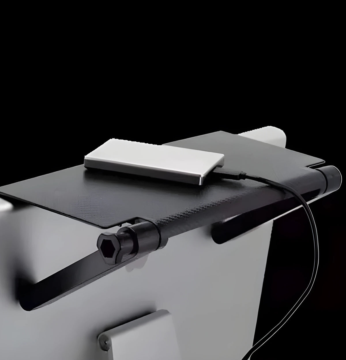 Black adjustable screen top shelf mounted on a monitor holding a streaming device and remote