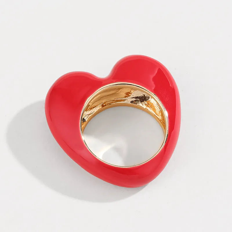Heart-shaped zinc alloy ring with colourful three-dimensional enamel details on a neutral background.