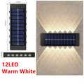 Black solar outdoor garden wall light with up and down glowing effect on a brick wall at night