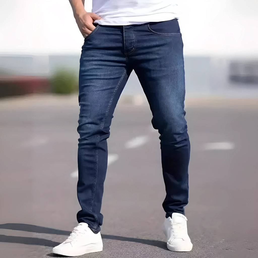 Man wearing dark blue slim-fit skinny jeans with a mid waist and zip fly.