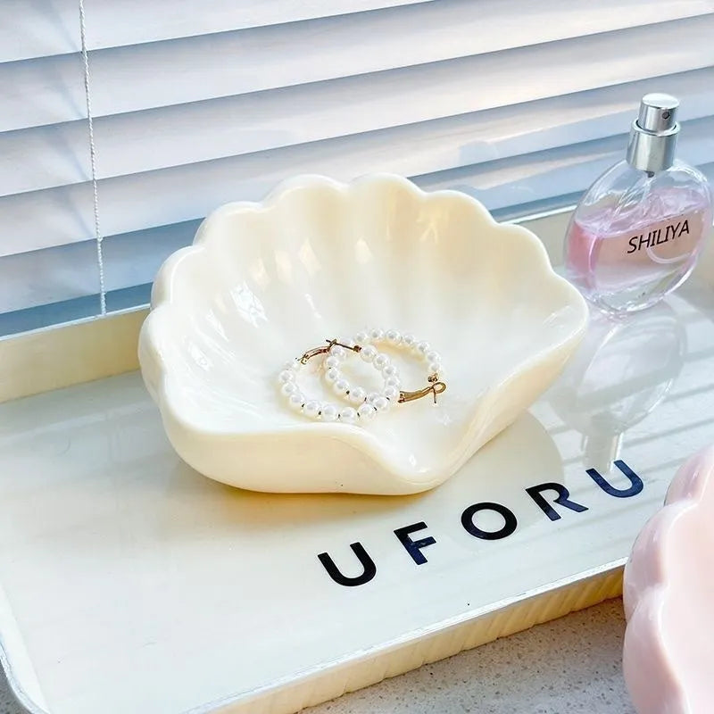 White shell-shaped plastic soap dish for bathroom counter next to sink.