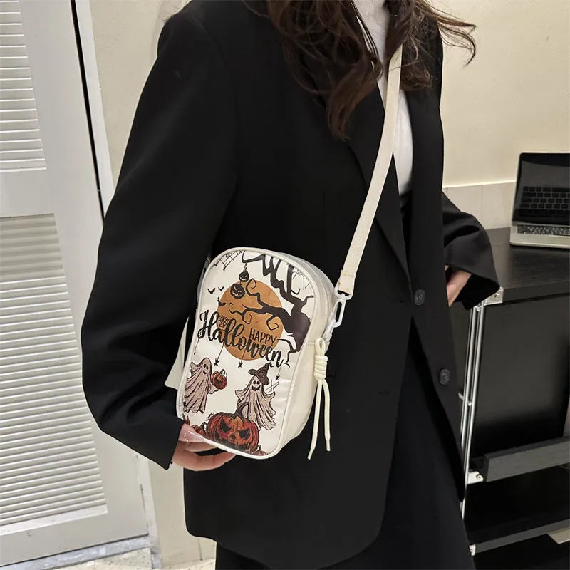 Black Halloween crossbody bag with cartoon pumpkin, ghost, and bat print, showing front and strap.