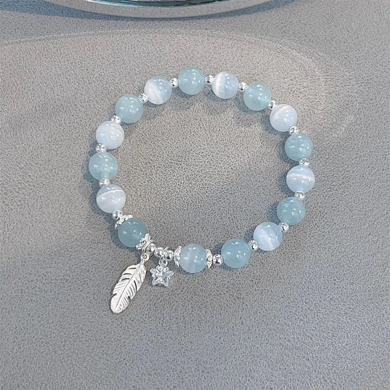 Korean style blue crystal bracelet with white lettering and a star charm on a wrist.