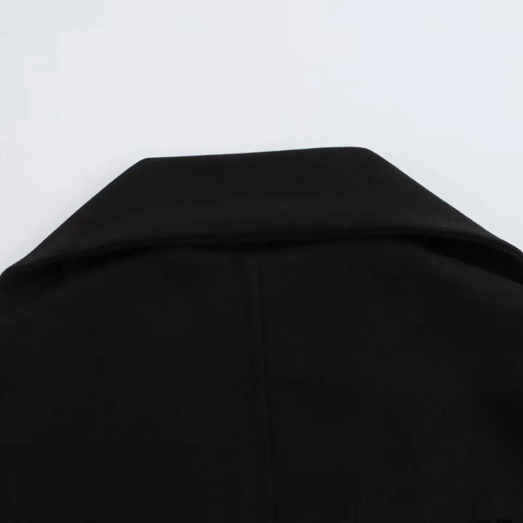 Women's long grey overcoat with artificial fur collar and pockets on a street-style backdrop.