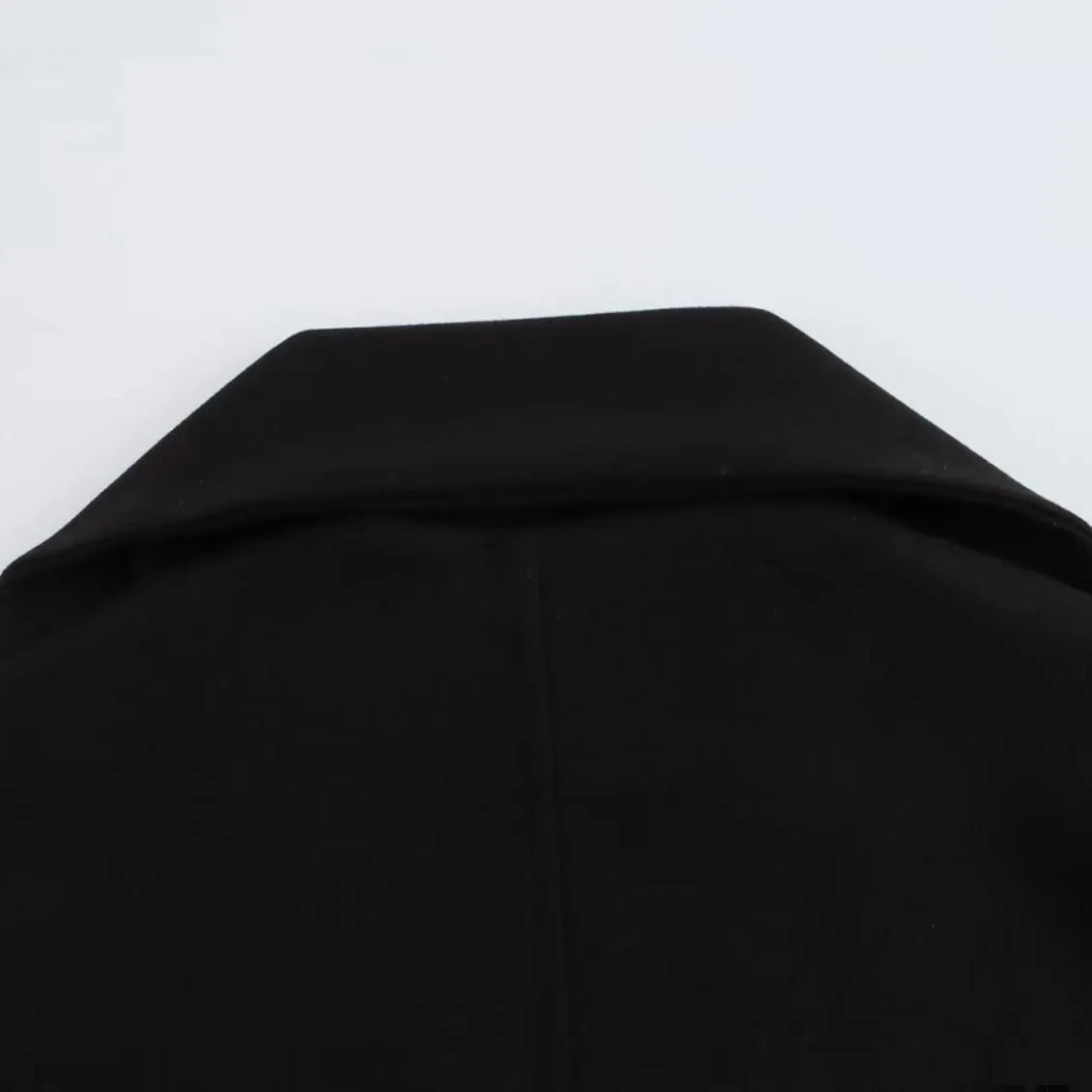 Women's long grey overcoat with artificial fur collar and pockets on a street-style backdrop.