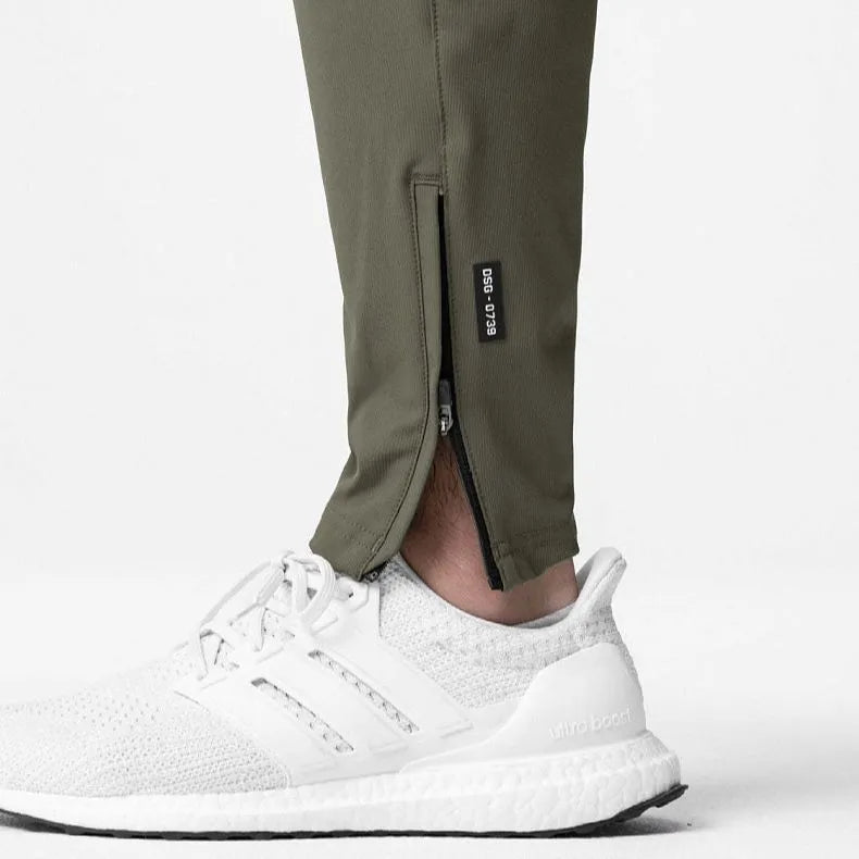 Man wearing dark grey loose-fit ankle-tied fitness trousers made of quick-drying polyester.