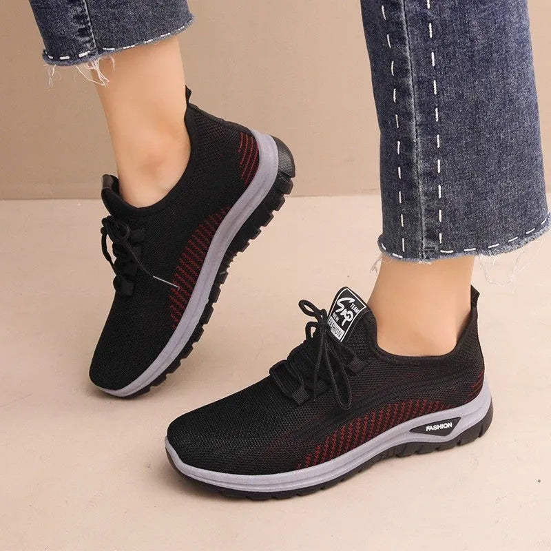 Women's black mesh sneakers with a cross-strap design and round toe, shown on a white background.