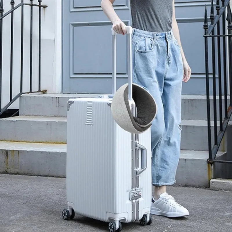 U-shaped navy blue memory foam travel neck pillow rolled up next to a mobile phone showing compact size