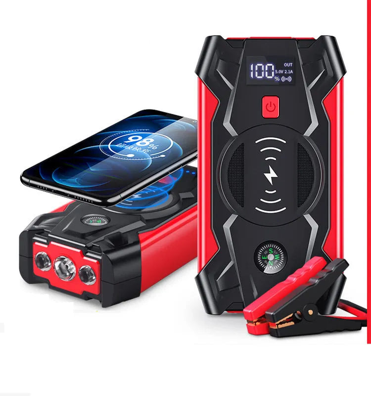 Red car emergency jump starter power pack with battery clamps and cables on a black storage box.
