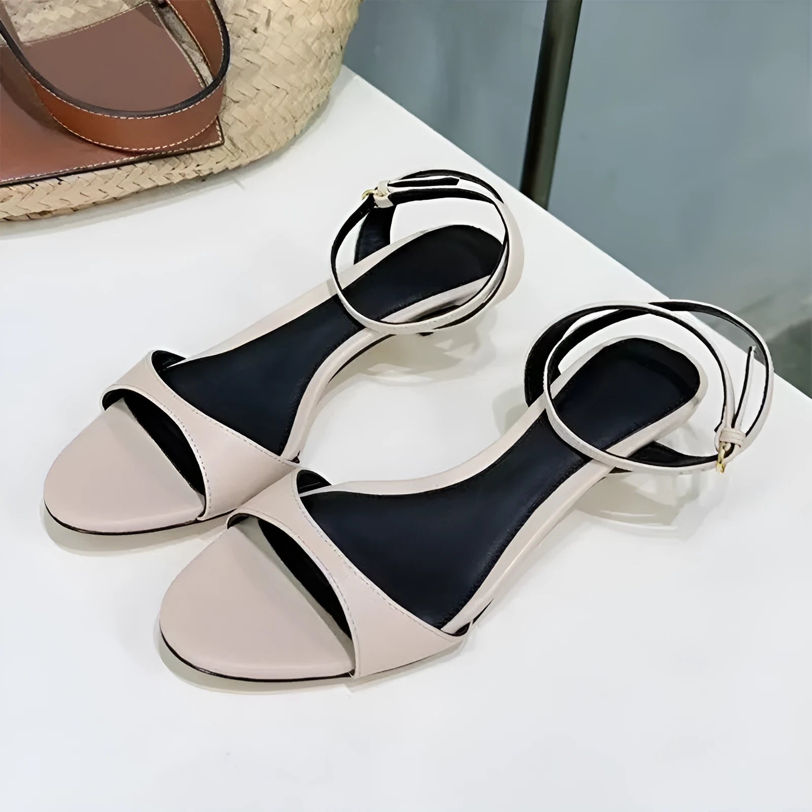 Women's black leather open-toe sandals with a buckle strap and a low kitten heel on a white background.