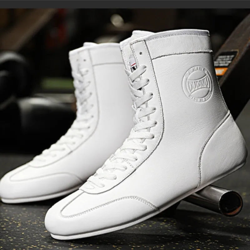 Black and gold mesh professional boxing shoes for men and women on a gym mat.