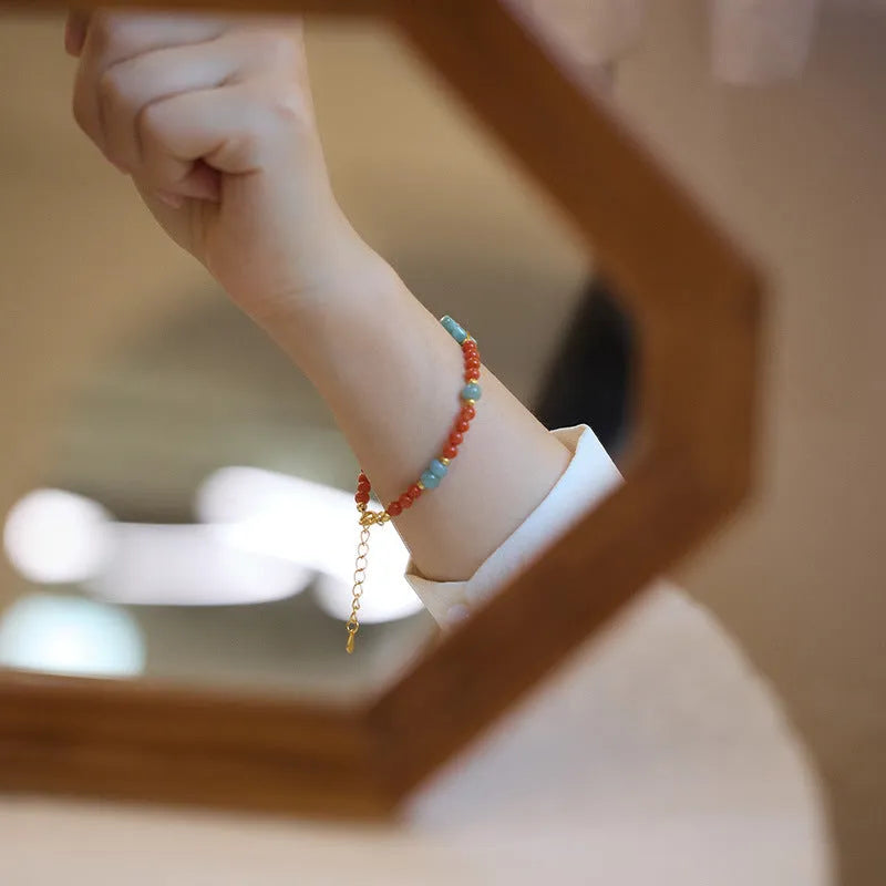 Close-up of a women's south red agate bracelet with geometric beads and a safety buckle clasp on a wrist.