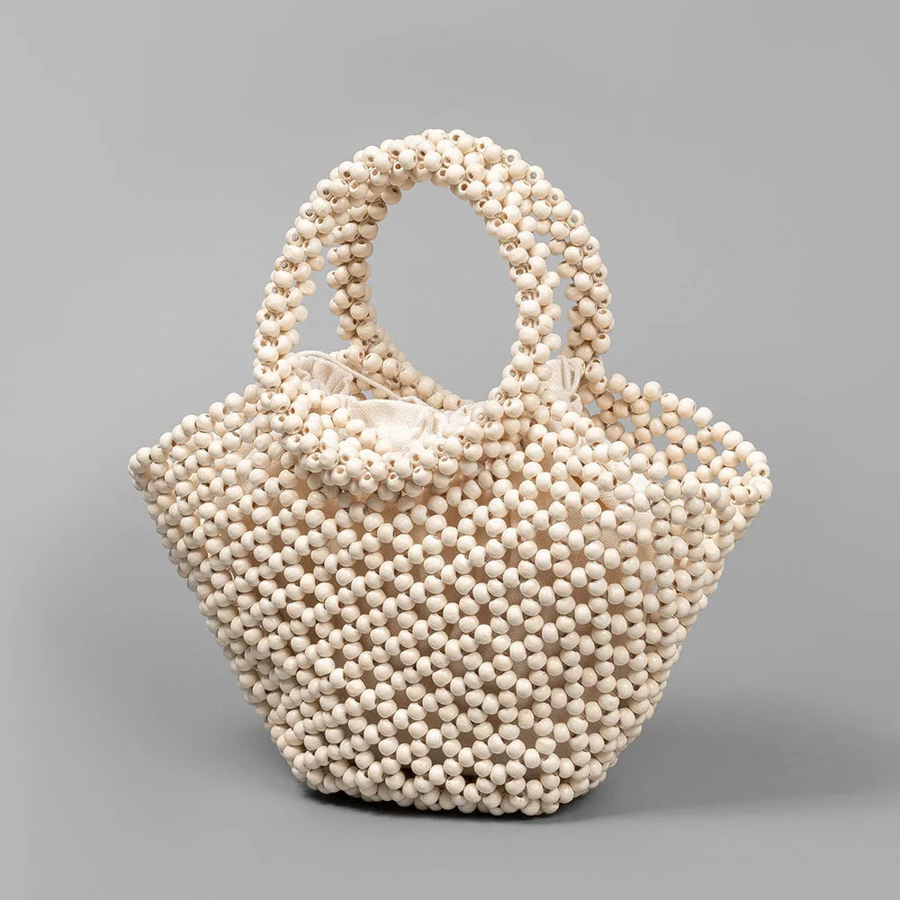 Hand-woven dumpling-shaped beach bag with wooden beads in milky white.