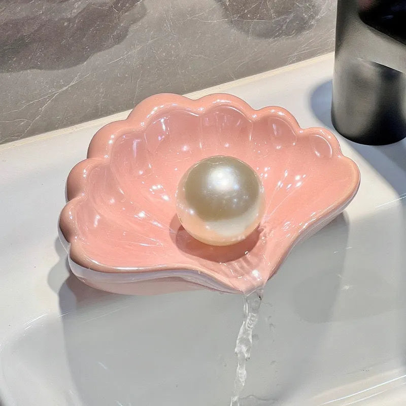 White shell-shaped plastic soap dish for bathroom counter next to sink.