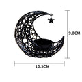 Gold metal crescent moon candle holder with hollow design on a dark surface