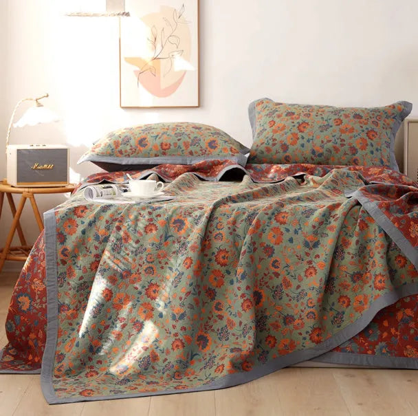 Cotton gauze bed blanket set with floral pattern and two matching pillowcases laid on a bed