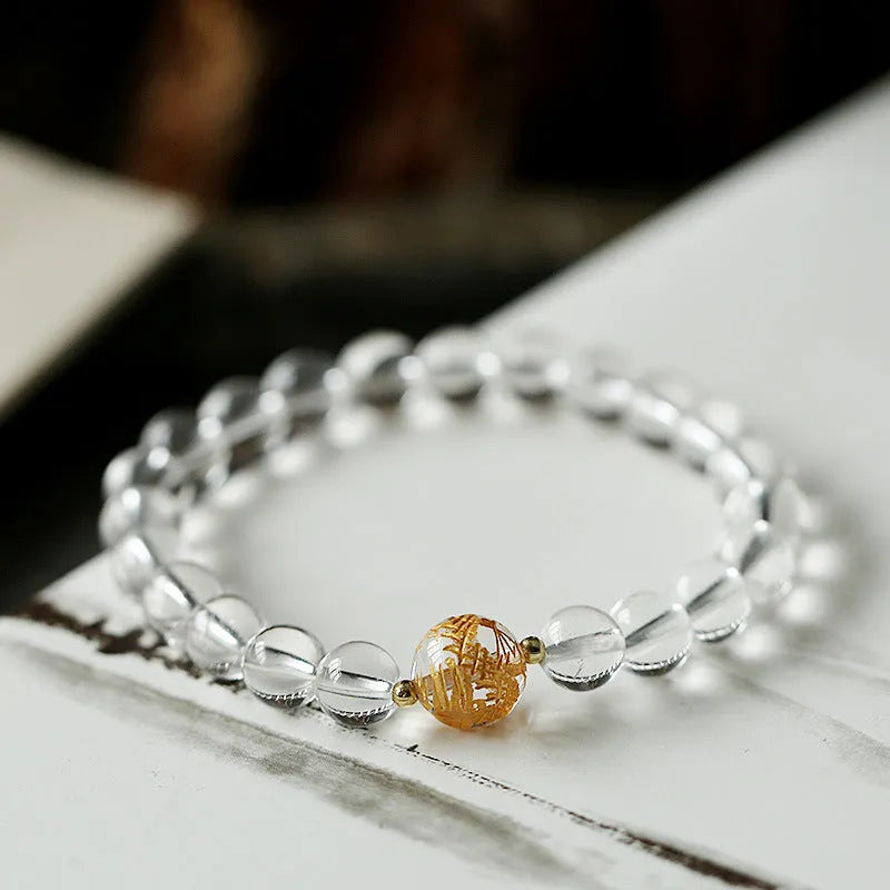 Geometric obsidian and white crystal bracelet with a golden dragon charm on a wrist.