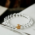 Geometric obsidian and white crystal bracelet with a golden dragon charm on a wrist.