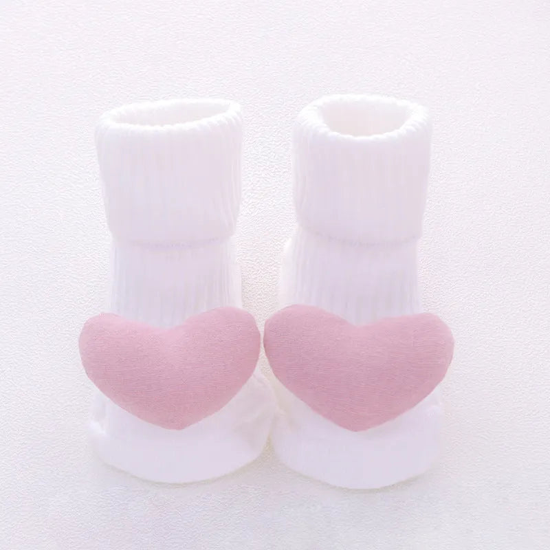 Cotton baby floor socks in a pink bow pattern, shown on an infant's feet.