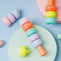 Set of six colourful cookie-shaped highlighter pens with macaron colours arranged on a white surface.