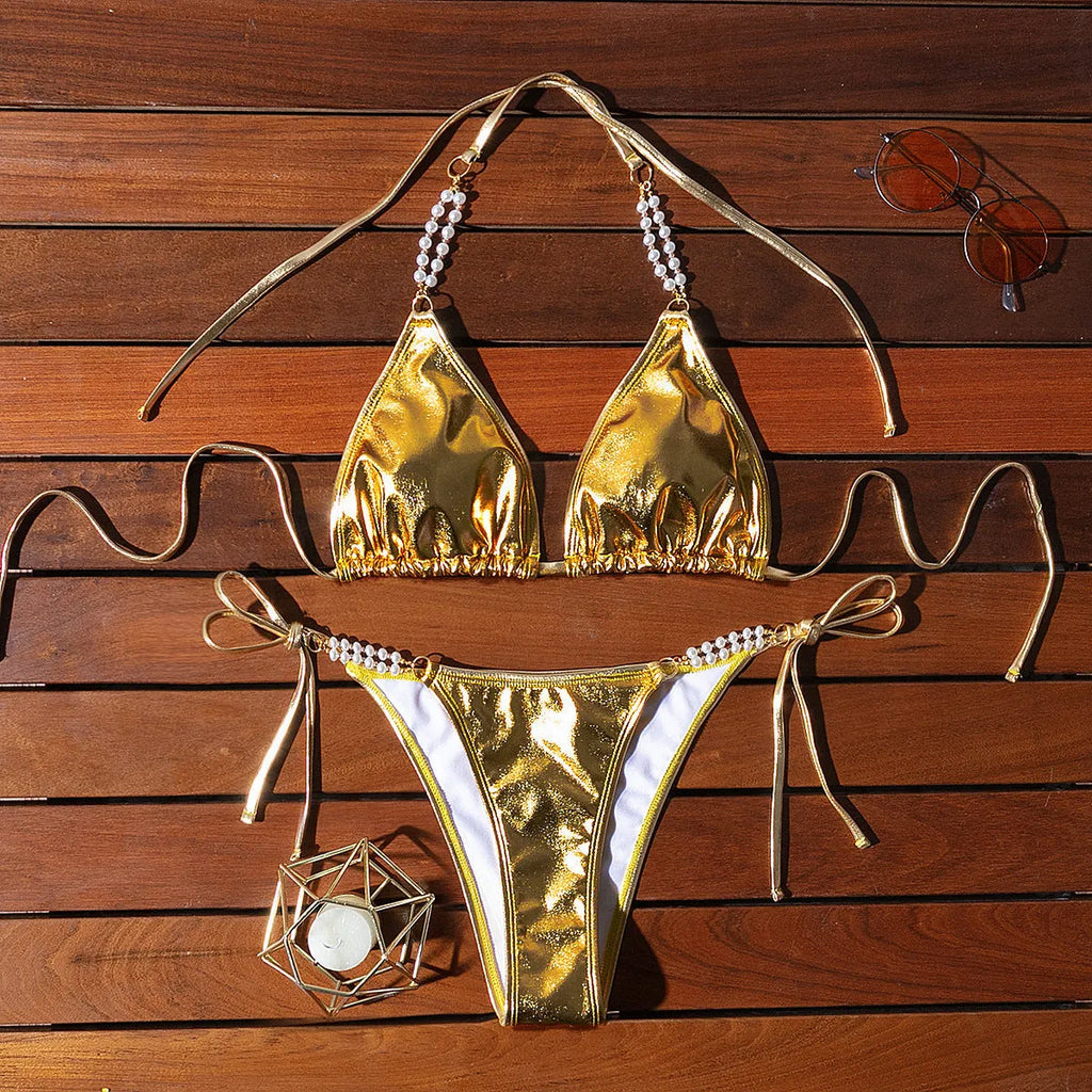 Gold halter neck bikini top with lace-up front and matching briefs, featuring pearl chain detail.