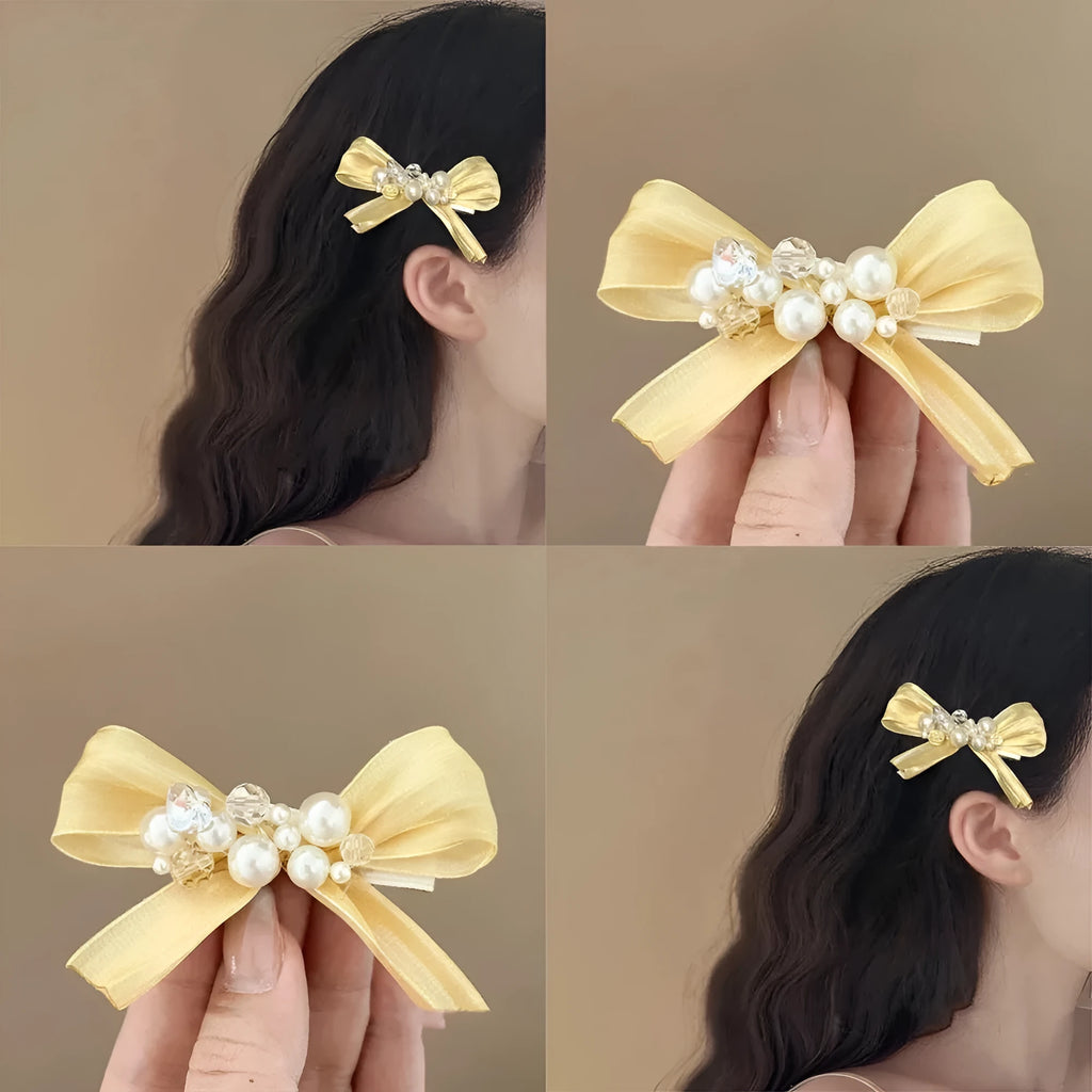 Yellow cloth bow hair clip with pearl accents on a duckbill clip.