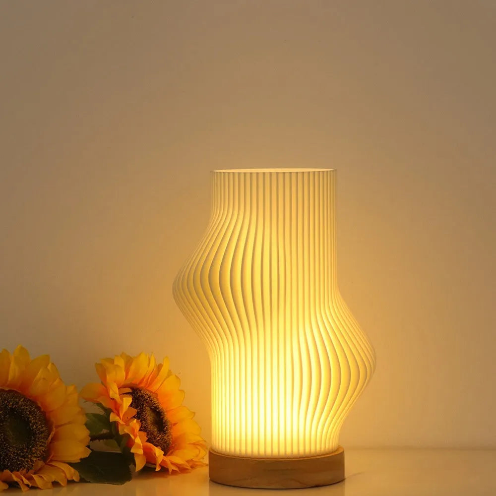 3D printed cylindrical vase night lamp with glass shade in wood colour finish on a bedside table