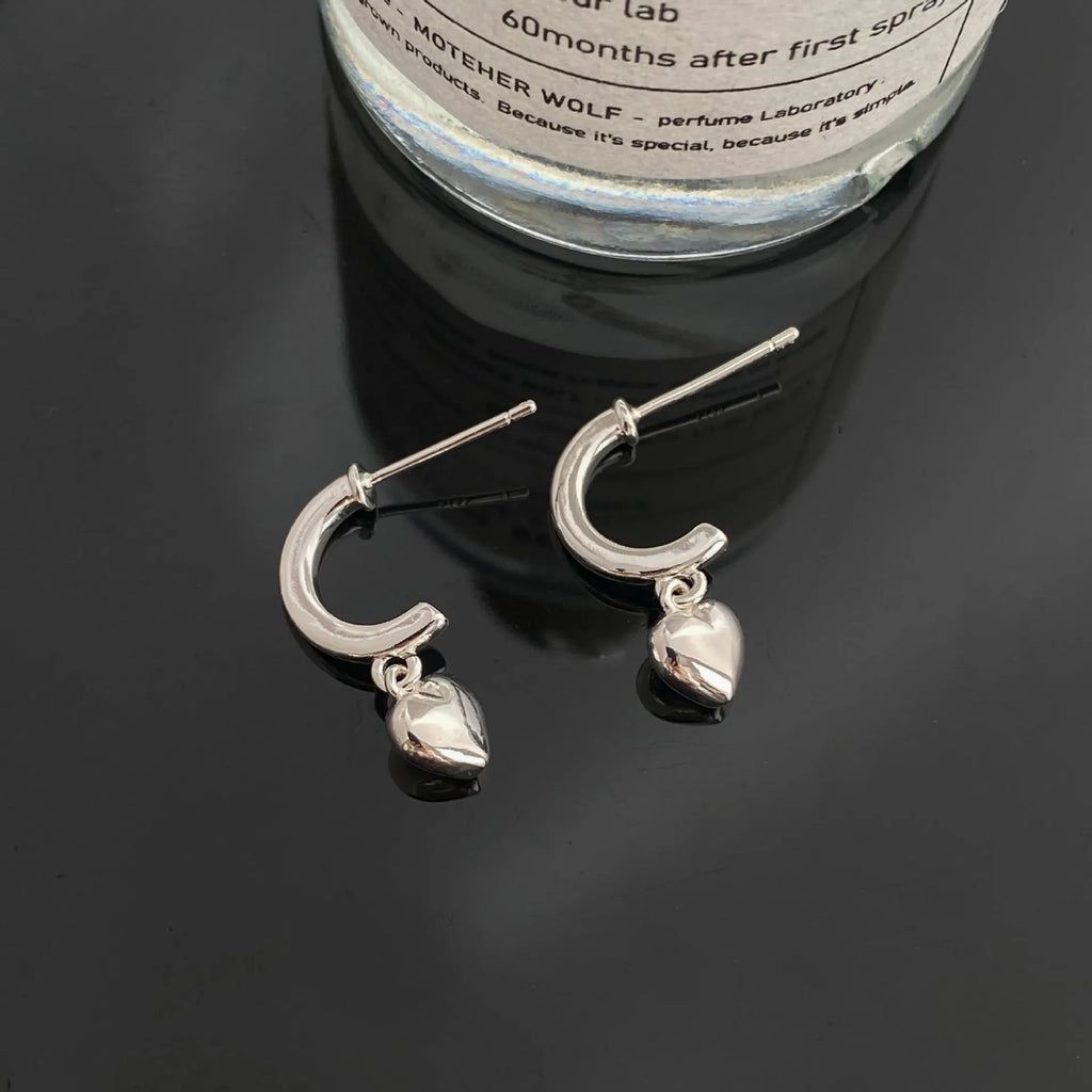 Pair of copper heart-shaped C-style earrings in gold electroplated finish on white background