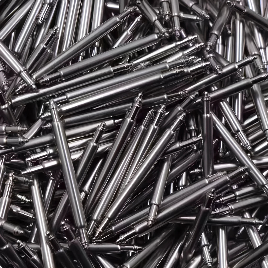 Assortment of watch repair parts including bolts, auricular needles, and spring shafts on a watchmaker's mat.