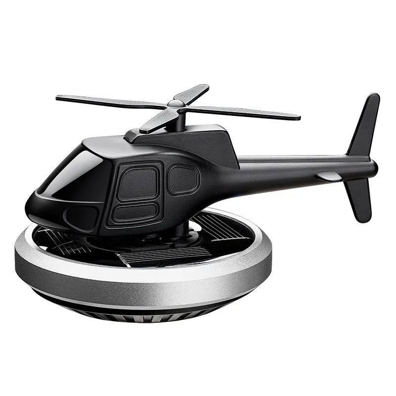 Silver metal solar-powered helicopter car air freshener rotating on a car dashboard.