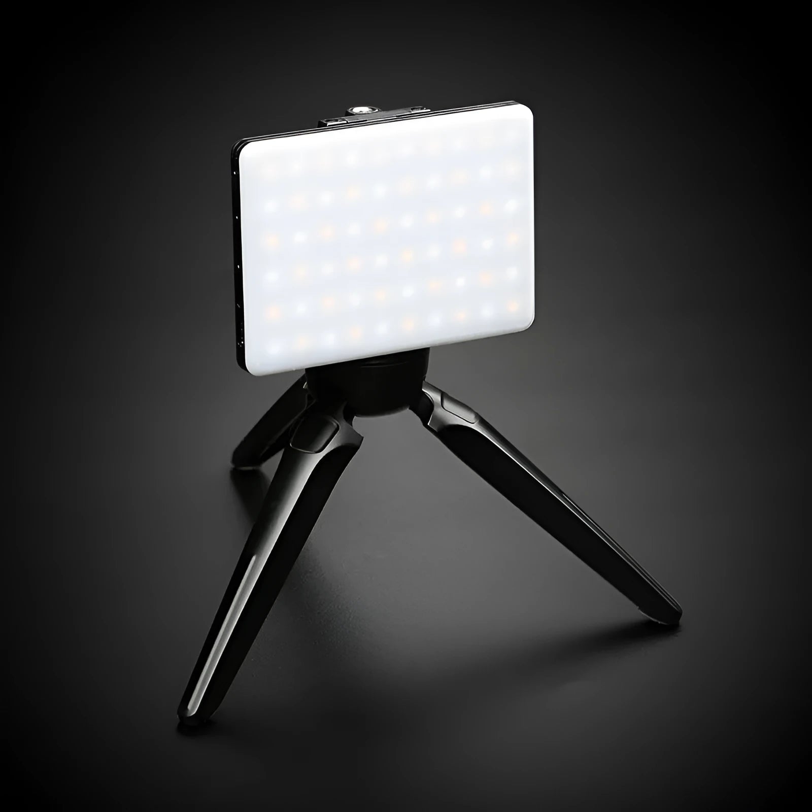 White portable LED fill light clipped to mobile phone with adjustment knob visible