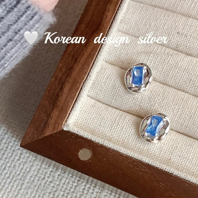 Women's sterling silver earrings with heart-wrapped oval blue diamond centrepiece on silver geometric design