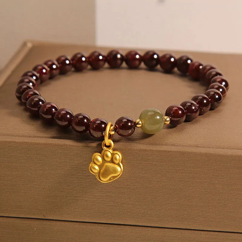 Women's original design Cat's Paw Garnet crystal bracelet on a plain background.