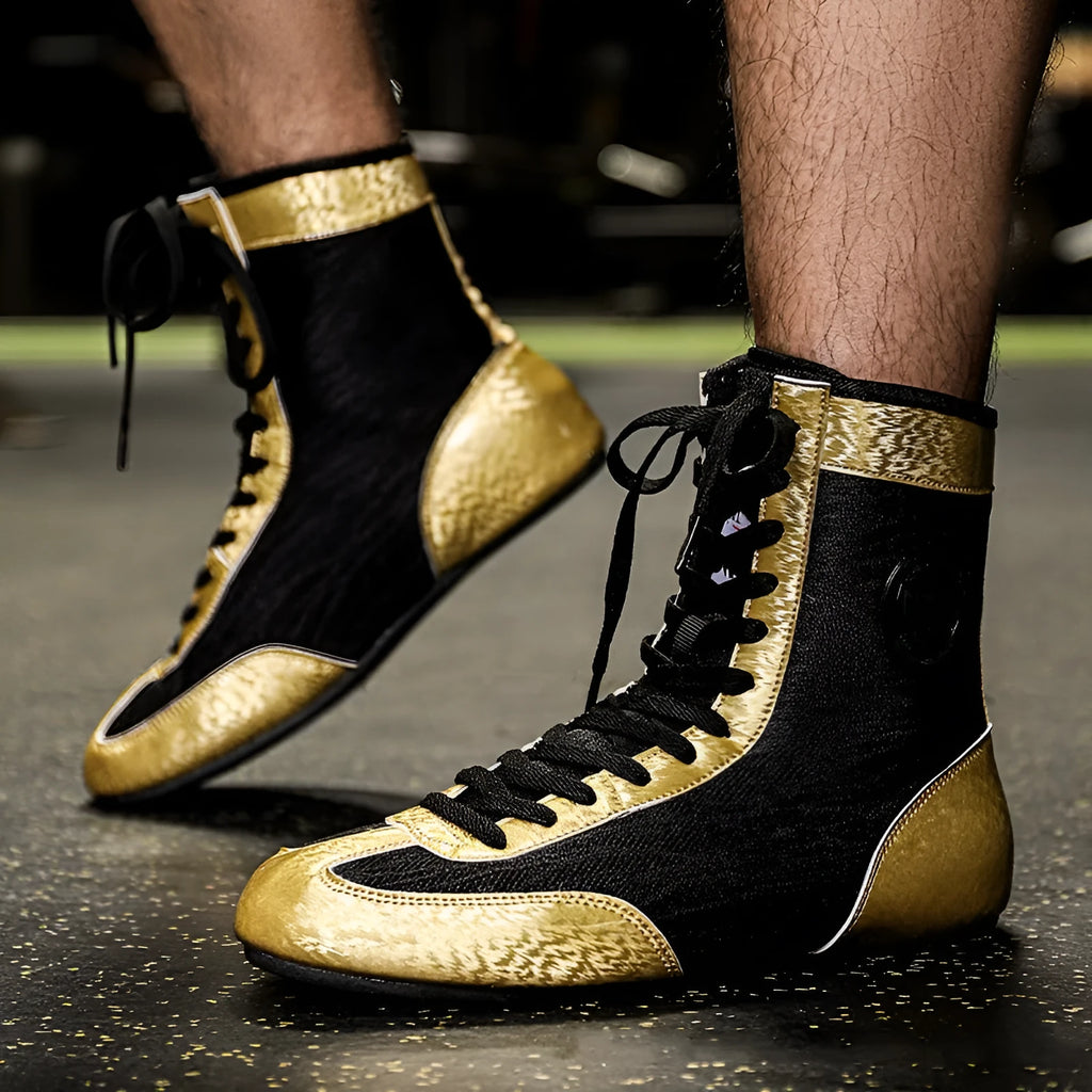 Black and gold mesh professional boxing shoes for men and women on a gym mat.