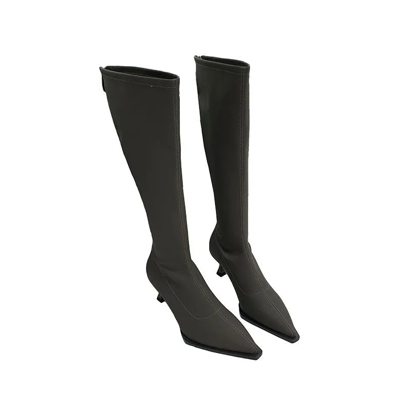 Black women's pointed toe below-the-knee boots with a stiletto heel and back zipper on a plain background.