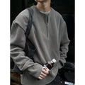 A woman's solid grey long sleeve loose fit pullover top on a hanger.