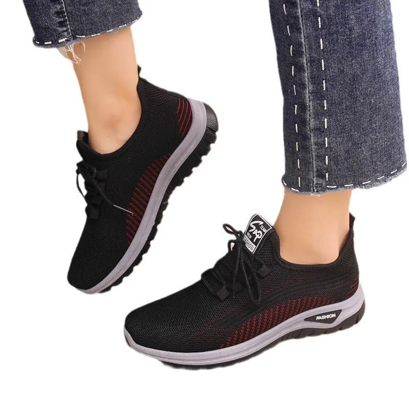 Women's black mesh sneakers with a cross-strap design and round toe, shown on a white background.