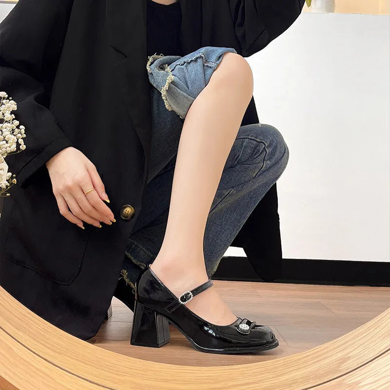 Women's black patent leather round toe chunky heels with a buckle strap, shown in a widened fit style.