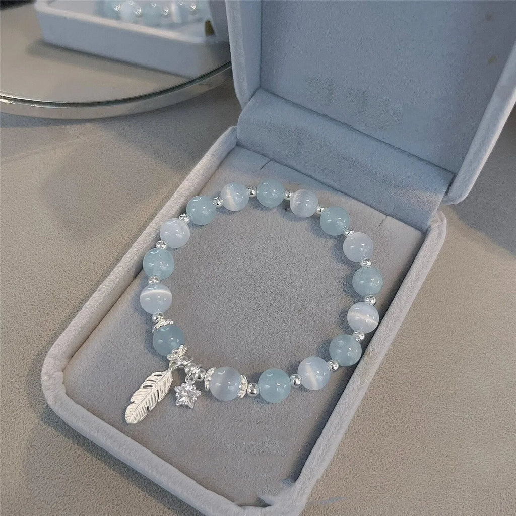 Korean style blue crystal bracelet with white lettering and a star charm on a wrist.